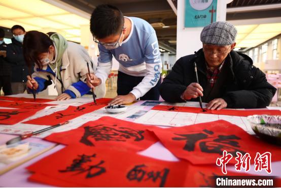 老教授和大学生一起写春联。　泱波 摄