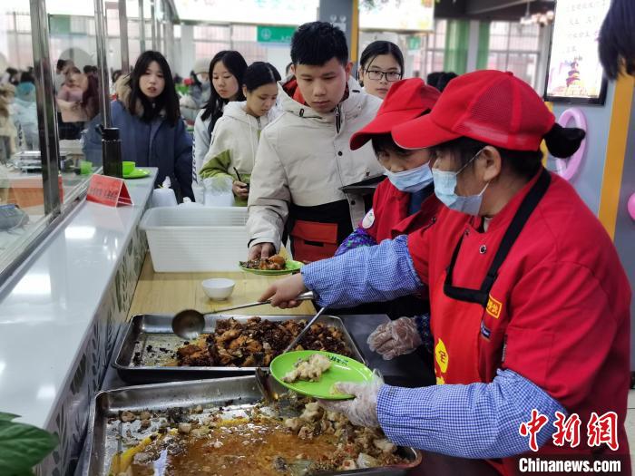 同学们在食堂排队领取用鱼烹调的菜品。　徐志雄 摄