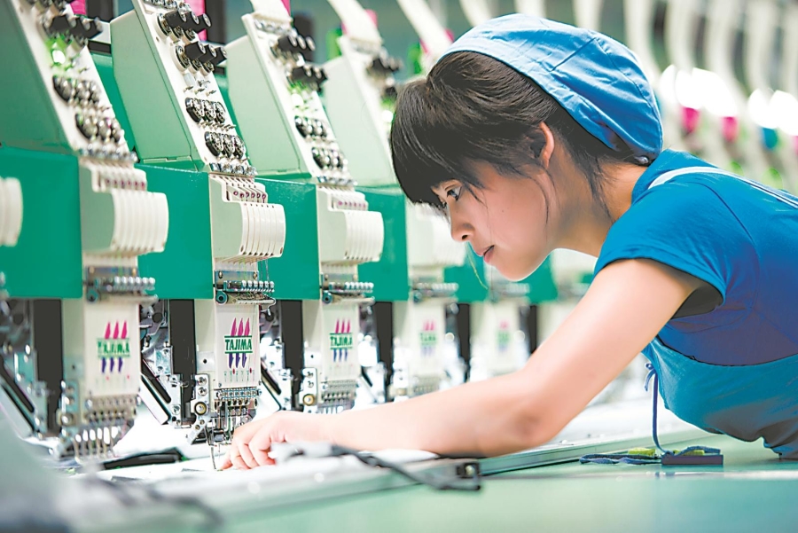 位于望江经开区的申洲针织(安徽)有限公司生产车间，纺织工正在检查设备。.jpg